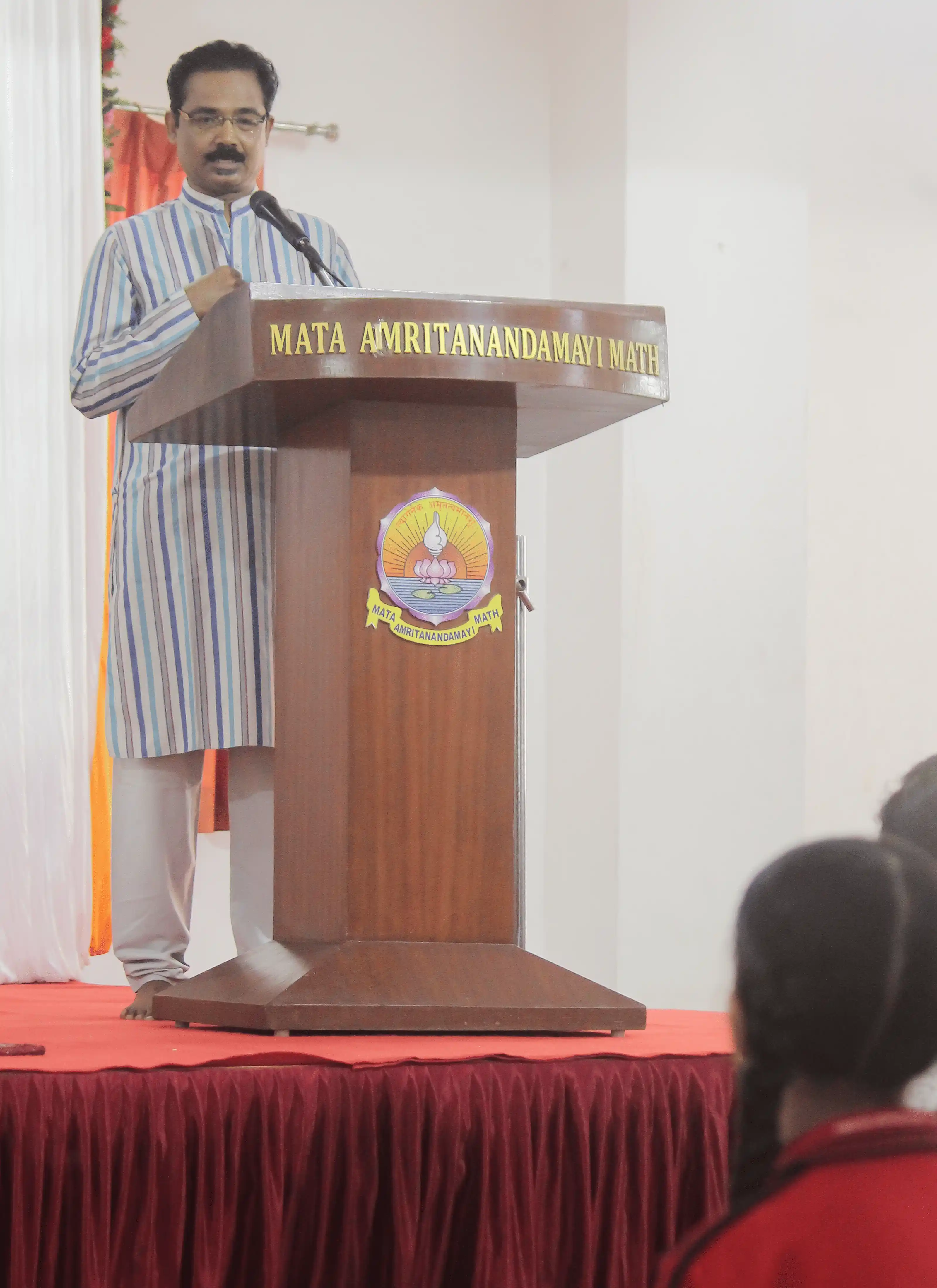 Speaker delivering a speech at a podium during a yoga event